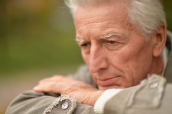Sad senior man posing in autumn park Portrait of sad senior man posing in autumn park